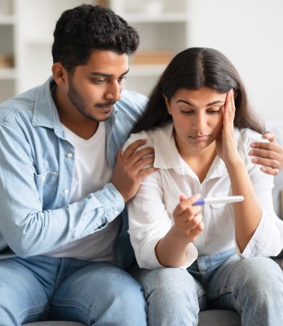 couple looking at pregnancy test on couch