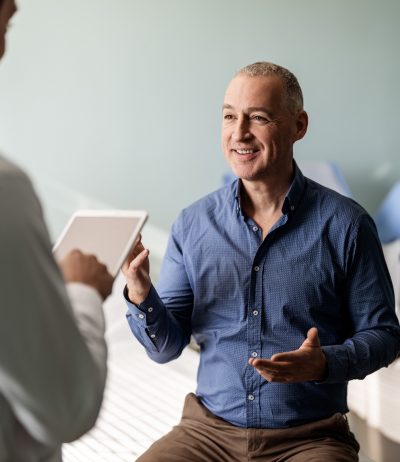 doctor talking with patient while holding tablet